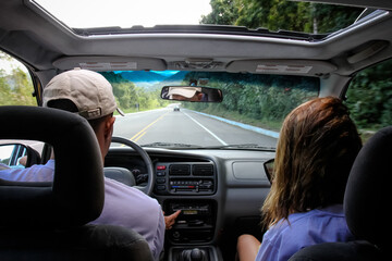 casal dentro de um carro com vista para asfalto.