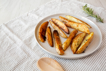 Homemade Rosemary Potato Wedges on a plate, side view. Copy space.