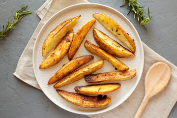 Homemade Rosemary Potato Wedges on a plate, top view. Flat lay, overhead, from above.