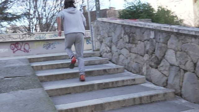 Man with long hair is running on the town stairs