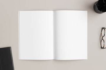 Open magazine mockup with a glasses and workspace accessories on the beige desk.