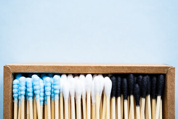 Eco friendly, minimalist composition of various bamboo cotton swabs in craft paper box on the blue background. Sustainable lifestyle concept, zero waste, plastic free.