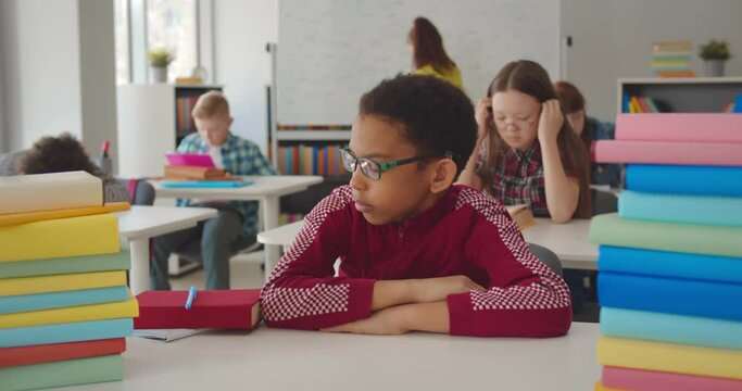 Portrait of afro-american schoolboy sleeping at desk in classroom