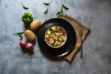 Indian snacks aloo jeera or boiled potatoes mixed with pepper and chopped onions in bowl on a background