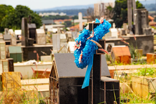Uma coroa de flores enfeitando uma cruz em túmulo no cemitério.