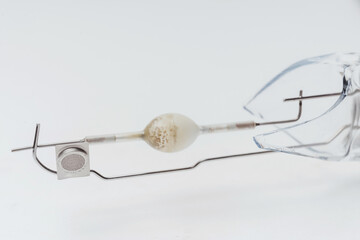 A broken halogen lamp on a white background. A discharge tube in a broken incandescent light bulb....