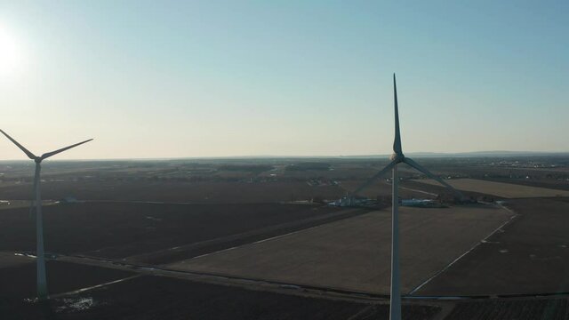drone panning over wind turbines in a wind farm with great sun in the back