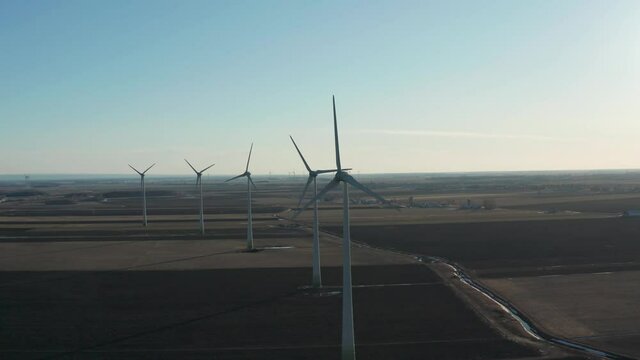 drone approaching wind turbines by the front in a huge wind farm in a sunny day