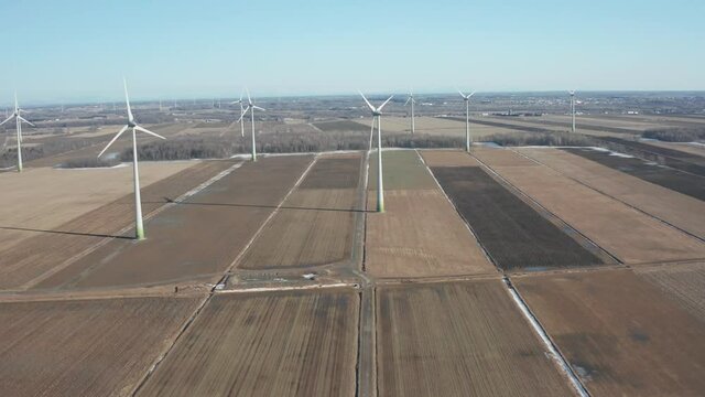 drone overlooking a wind farm turbines moving from donw to up overlloking the place in a sunny day