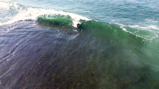 Drone pan shot of surfing wave barrel bodyboarder on ocean reef Central Coast NSW Australia 3840x2160 4K