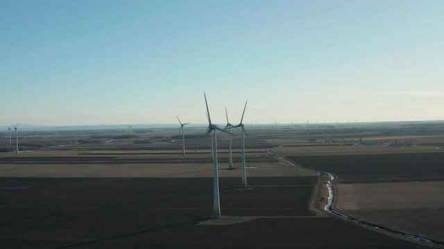 drone approaching some wind turbines by the front of the turbines and showing the rest of the wind farm