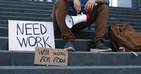 Carton tables with slogans Need work and Will work for food on stairs at man who sitting in despair with empty wallet in hands. Male with no money.