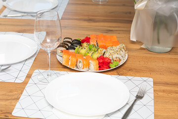 Delicious japanese rolls on a plate on the table and a glass of wine