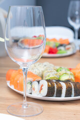 Delicious japanese rolls on a plate on the table and a glass of wine