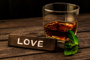 Glass of brandy with mint sprig and the wooden plank on it is an inscription 