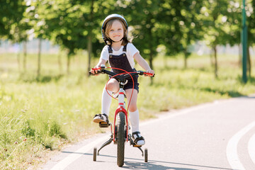 Cheerful smiling girl in helmet on bicycle.