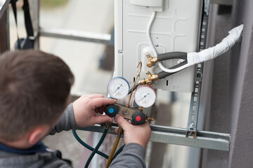 Technician vacuum pump evacuates and checking new air conditioner.