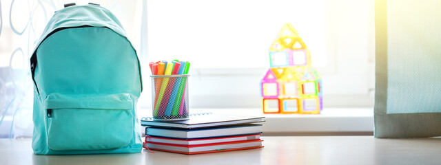 Banner. Concept back to school. Full turquoise School Backpack with stationery on table.