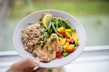 Hand holding a chicken and buckwheat dish with green beans