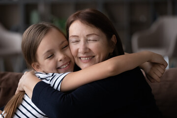 Close up of smiling loving elderly grandmother and teen granddaughter hug show family care support. Happy small teenage girl child embrace mature granny feel grateful and thankful. Gratitude concept.