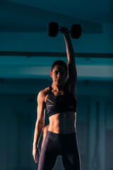 A fit young woman exercising with a dumbbell