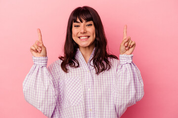 Young caucasian woman isolated on pink background indicates with both fore fingers up showing a blank space.