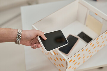 Close up of unrecognizable teenager putting smartphone in box in no gadget classroom at school,...