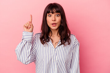 Young caucasian woman isolated on pink background pointing upside with opened mouth.