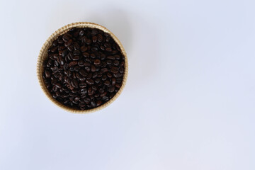 Coffee beans in wicker basket isolated on white background closeup.