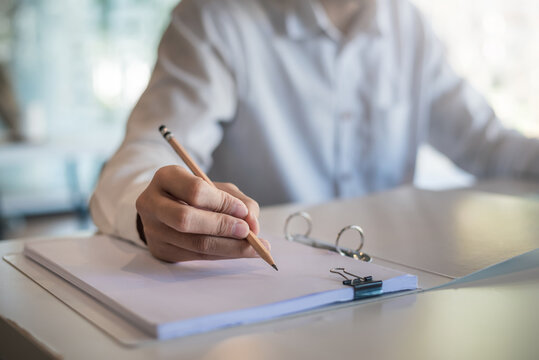 Close Up Of A Woman Holding A Pencil Taking Notes At The Office.