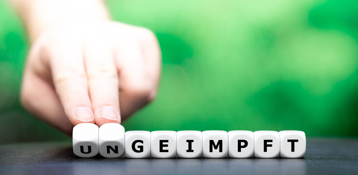Hand turns dice and changes the German word "ungeimpft" (unvaccinated) to "geimpft" (vaccinated).