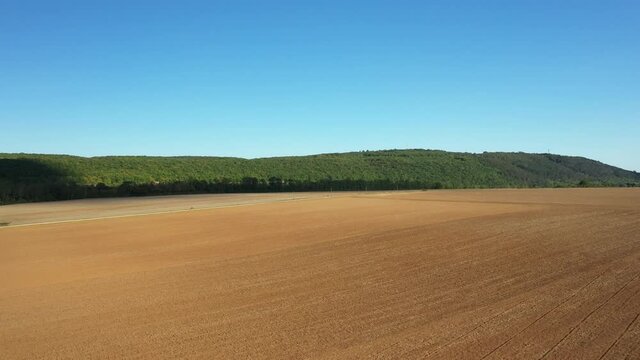 Les champs de bl&eacute; apr&egrave;s la moisson entour&eacute;s de for&ecirc;ts verdoyantes  vers Nevers, dans la Ni&egrave;vre, en Bourgogne, en France, &agrave; l'&eacute;t&eacute;, en drone sous un beau ciel bleu.