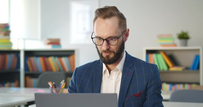 Close up portrait of school teacher typing report on laptop