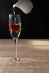 Ripe red strawberry in a glass of water. Splash in water on black background. Copy space