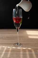 Ripe red strawberry in a glass of water. Splash in water on black background. Copy space