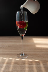 Ripe red strawberry in a glass of water. Splash in water on black background. Copy space