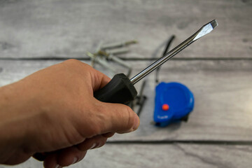 Fototapeta na wymiar A black locksmith screwdriver in his hand on a gray background.