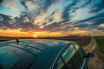 top view of a car on a rural country road against the background of a dramatic sunset sky
