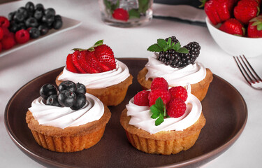Tartlets with meringue and fresh berries / raspberries, strawberries, blueberries and blackberries/ Delicious dessert.