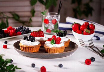 Tartlets with meringue and fresh berries / raspberries, strawberries, blueberries and blackberries/ Delicious dessert.