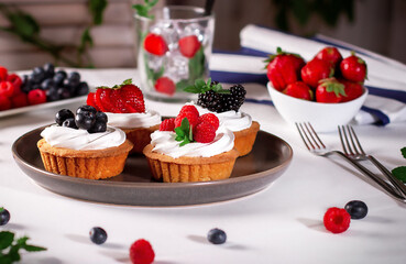 Tartlets with meringue and fresh berries / raspberries, strawberries, blueberries and blackberries/ Delicious dessert.