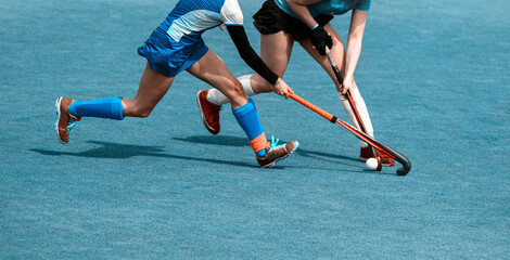 Two field hockey player, fighting for the ball on the midfield during an intense match on green...