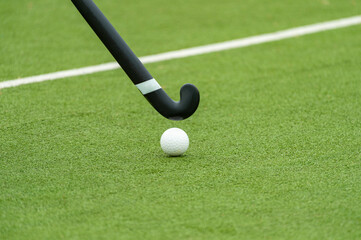 Field hockey stick and ball on green grass. Professional sport concept