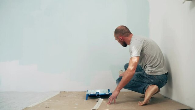 Caucasian man paints the wall with a brush Dad makes repairs in the room Quality work Close up