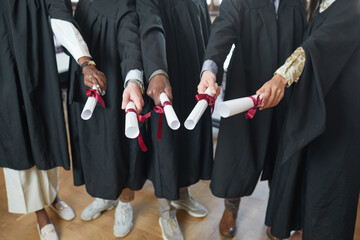 High angle view at multi-ethnic group of young people wearing graduation robes and pointing...