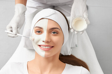 Top view portrait of smiling beautiful woman on procedure cleaning face in beautician. Concept of...