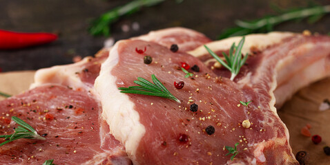 Raw meat for steak with ingredients for cooking on a dark background. Chop on the bone.