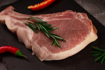Raw meat for steak with ingredients for cooking on a dark background. Chop on the bone.