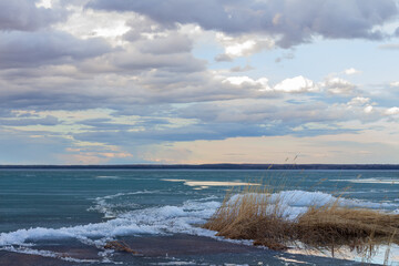 clouds over the beach in spring thaw of lake