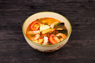 tomato soup with mussels, fish, shrimp, served with tomatoes, pineapple and greens